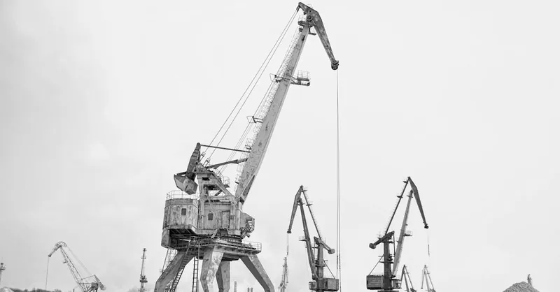 Black and white photo of industrial cranes at a construction site, showcasing heavy equipment.