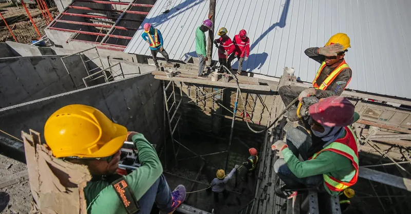 Construction workers wearing helmets and vests on a busy site, focusing on safety and teamwork.