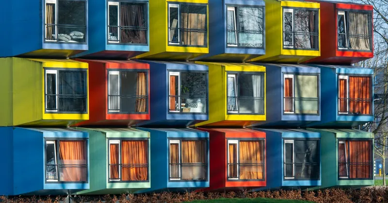 Vibrant exterior of colorful modular housing units with varied window designs.