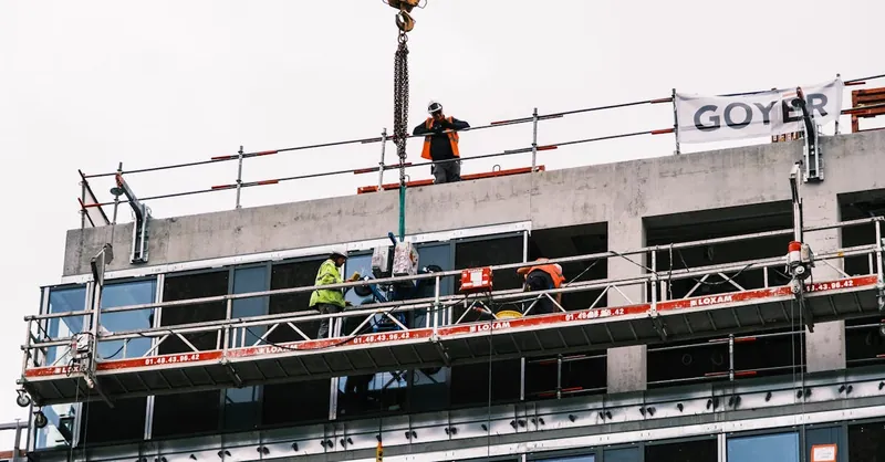 Professional workers at a construction site managing equipment on a high-rise building.