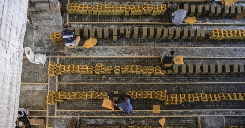 Top view of workers aligning clay bricks in a construction setting.