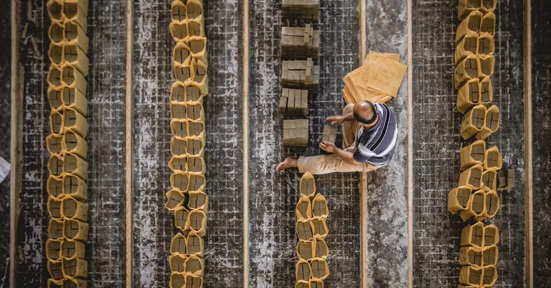 Top view of a man arranging bricks in rows, showcasing construction precision outdoors.