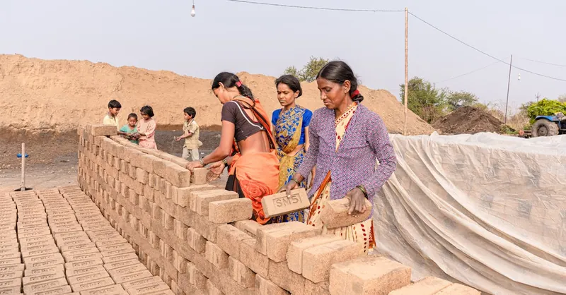 Women constructing a brick wall outdoors, symbolizing teamwork in rural settings.