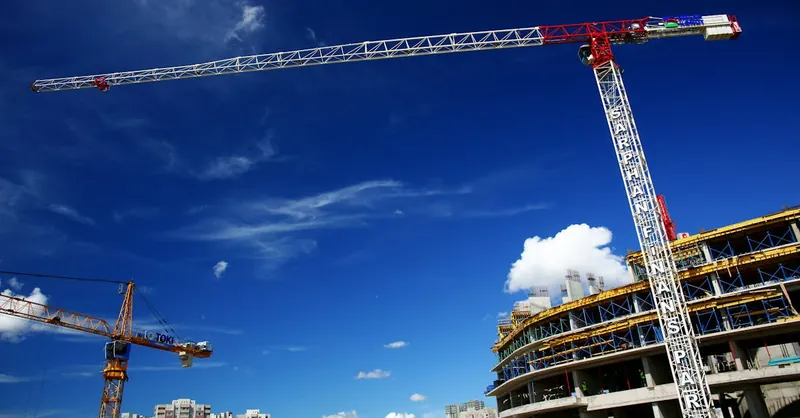 Tower cranes towering over a city skyline, showcasing ongoing urban construction.