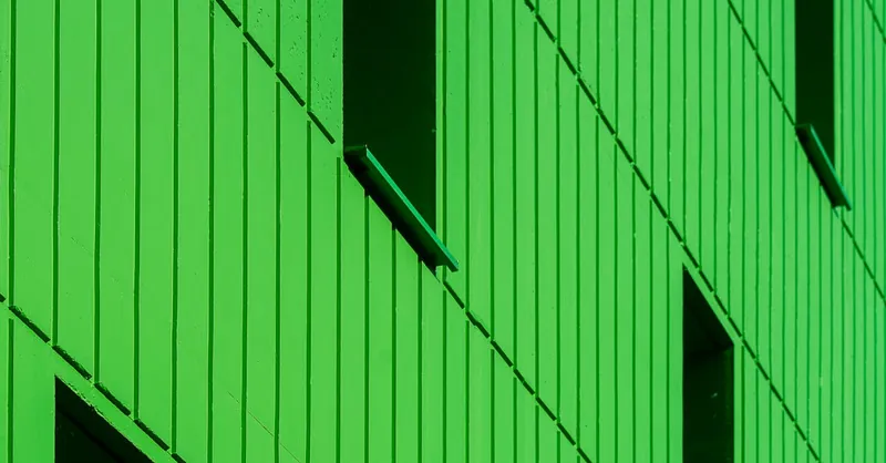 Bright green facade of modern architecture with windows for a contemporary look.