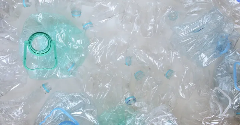 Top-view of crushed plastic bottles prepared for recycling, promoting sustainability.