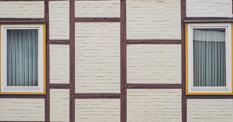 Detailed view of a half-timbered wall with two windows, highlighting traditional architecture.